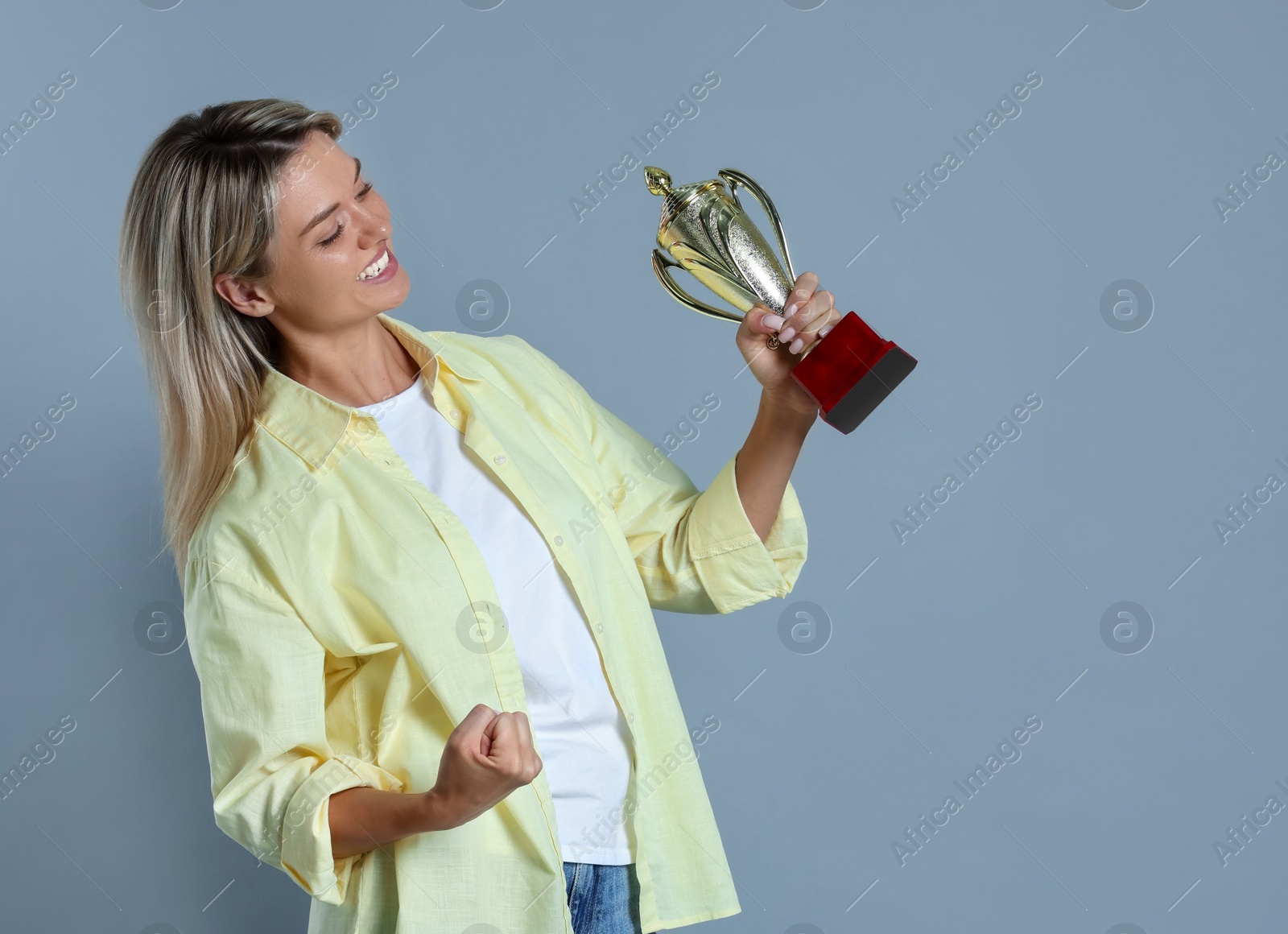 Photo of Happy winner with golden trophy cup on gray background,