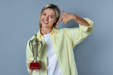 Photo of Happy winner with golden trophy cup on gray background,