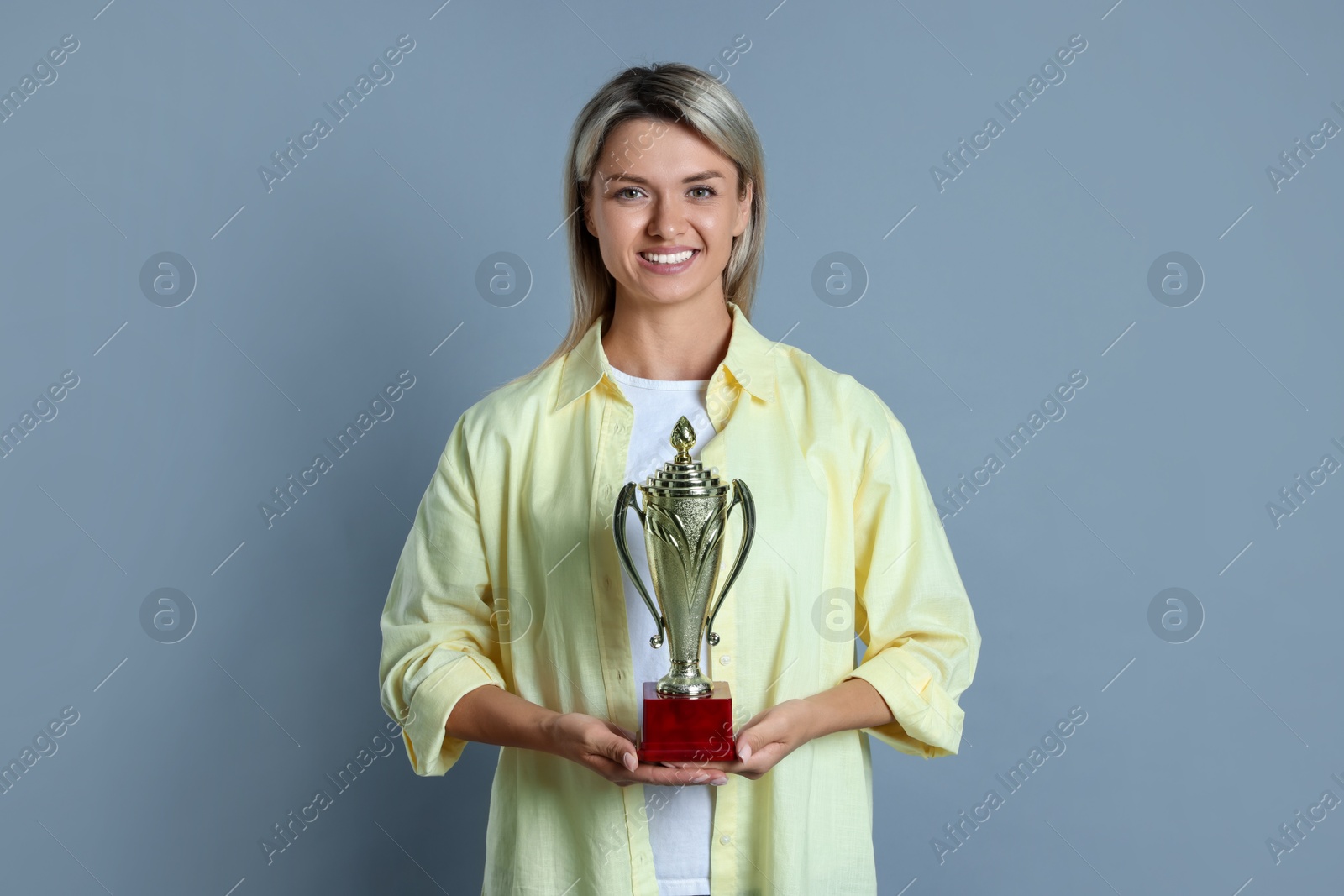 Photo of Happy winner with golden trophy cup on gray background,