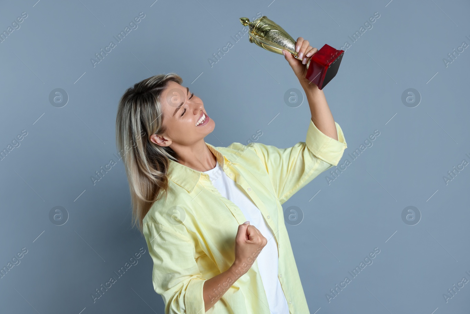 Photo of Happy winner with golden trophy cup on gray background,