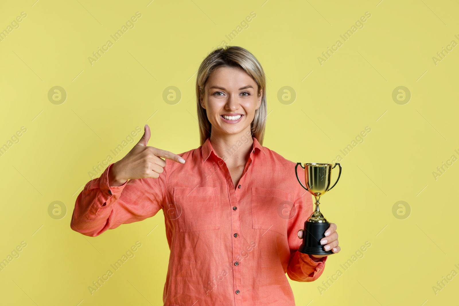 Photo of Happy winner with golden trophy cup on yellow background