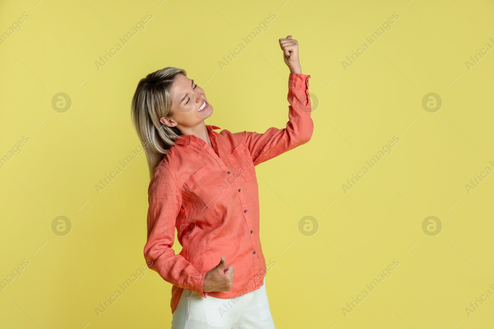 Photo of Portrait of happy winner on yellow background