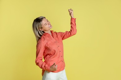 Photo of Portrait of happy winner on yellow background