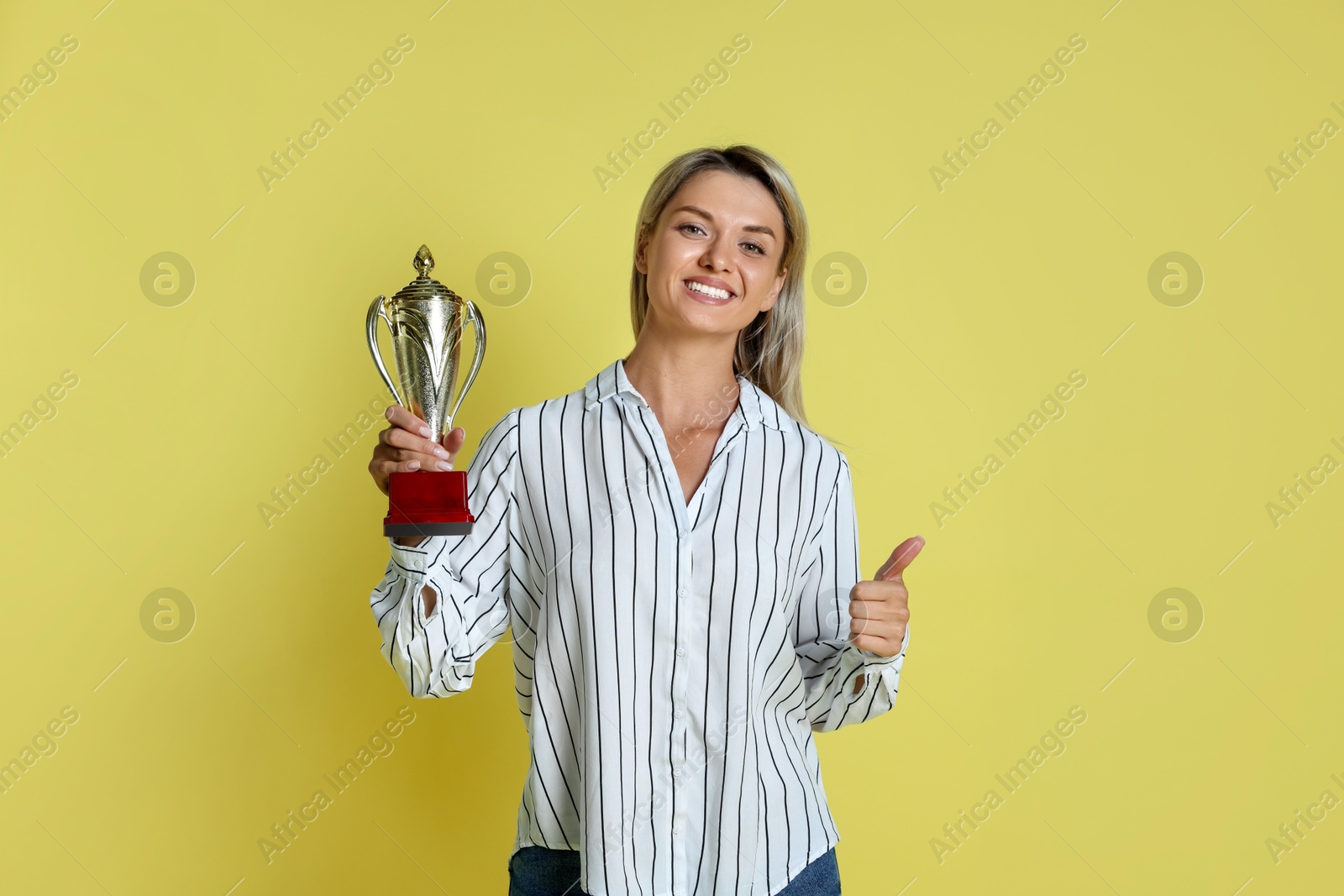 Photo of Happy winner with golden trophy cup on yellow background