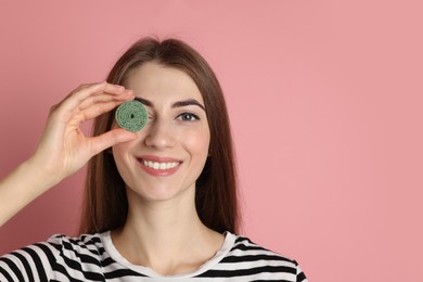 Happy young woman with tasty gummy candy on pink background, space for text