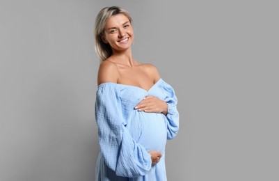 Portrait of beautiful pregnant woman on grey background