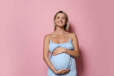 Portrait of beautiful pregnant woman on pink background