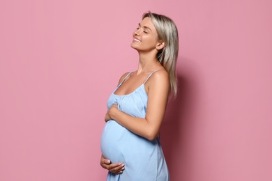 Portrait of beautiful pregnant woman on pink background