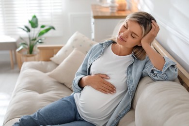 Portrait of beautiful pregnant woman on sofa at home