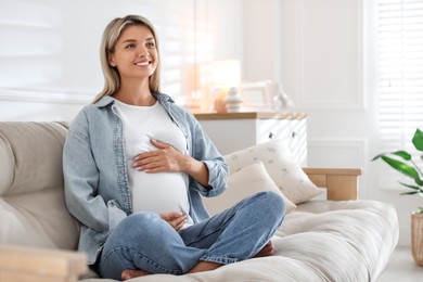 Photo of Portrait of beautiful pregnant woman on sofa at home