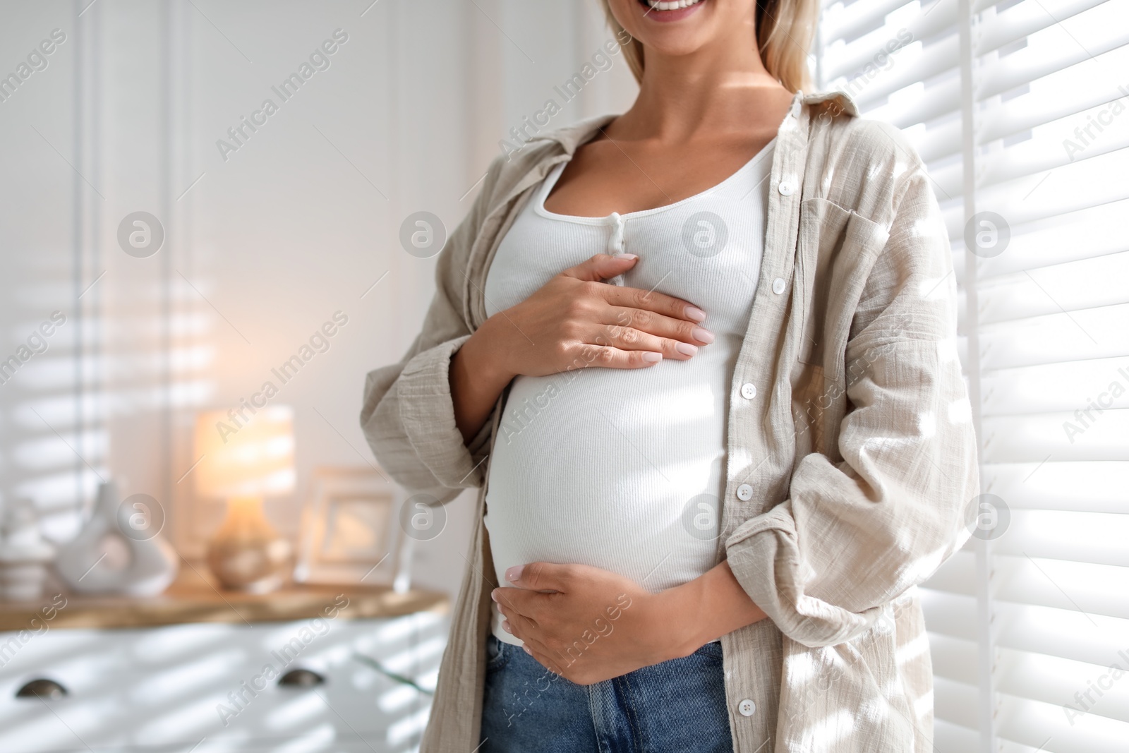 Photo of Pregnant woman near window at home, closeup. Space for text