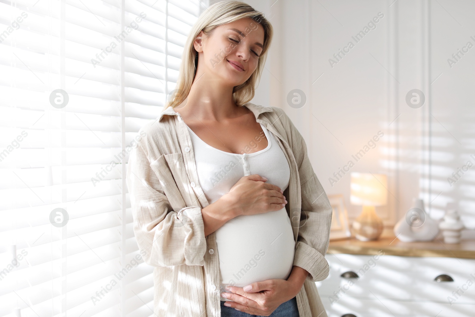 Photo of Portrait of beautiful pregnant woman near window at home