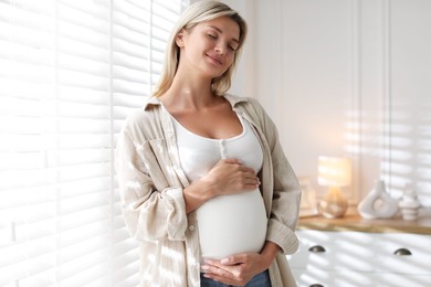 Photo of Portrait of beautiful pregnant woman near window at home