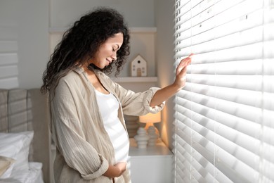 Portrait of beautiful pregnant woman near window at home