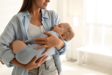 Mother holding her sleeping baby at home, closeup. Space for text