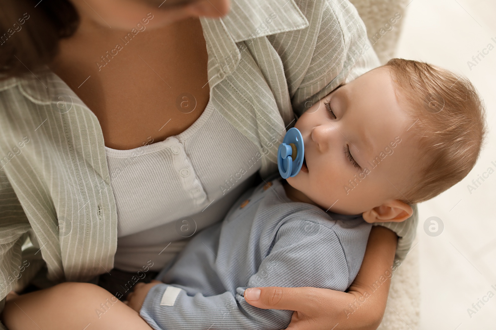 Photo of Mother with her sleeping baby in armchair indoors, closeup