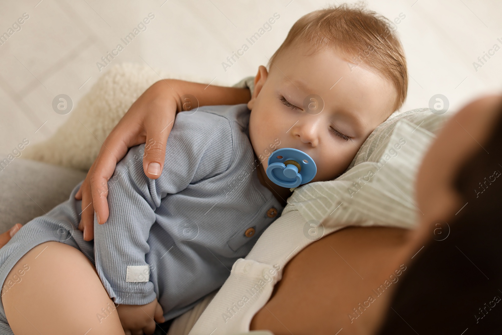 Photo of Mother with her sleeping baby in armchair indoors