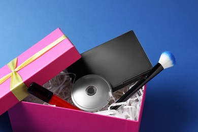 Photo of Gift box with decorative cosmetics on blue background, closeup