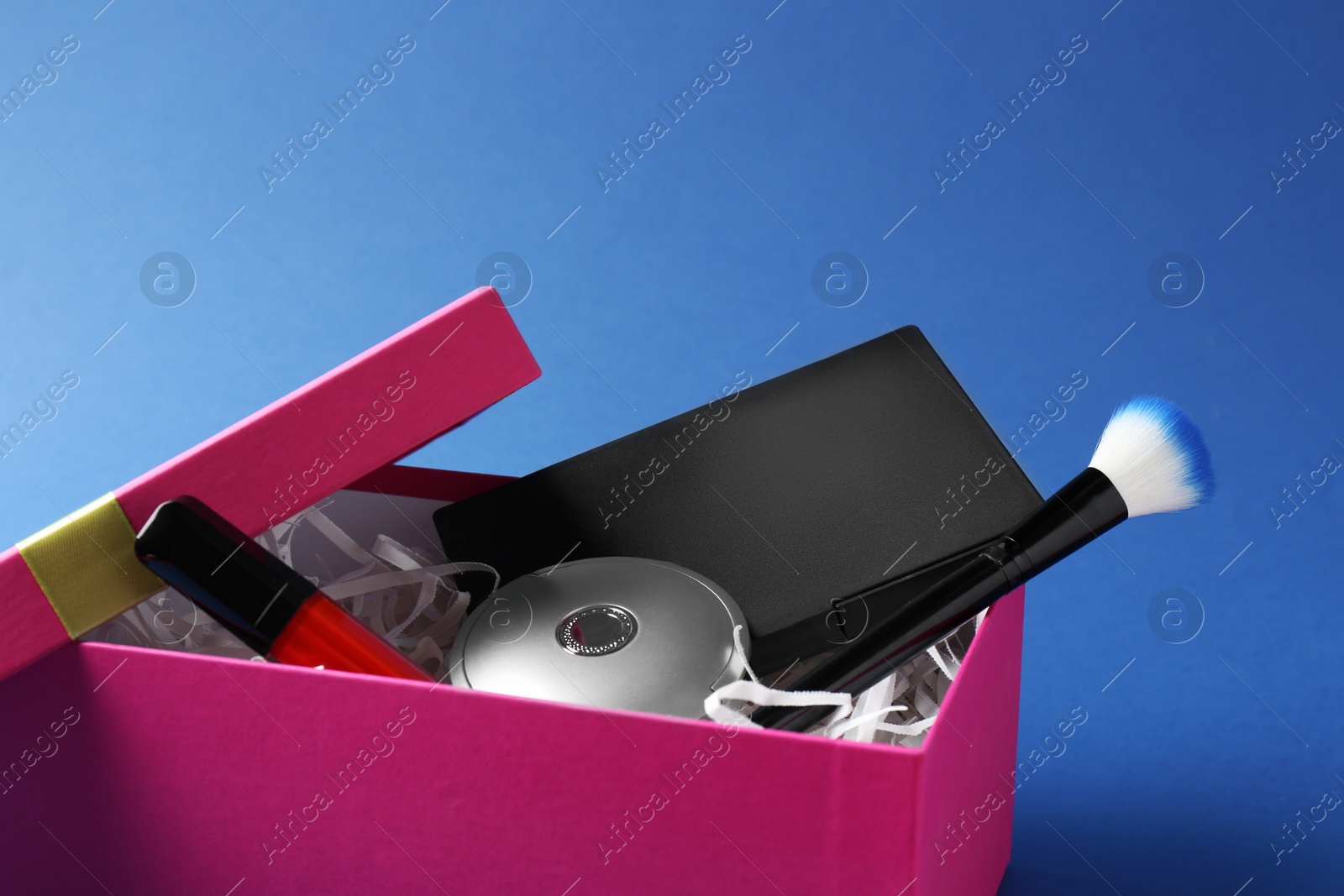 Photo of Gift box with decorative cosmetics on blue background, closeup