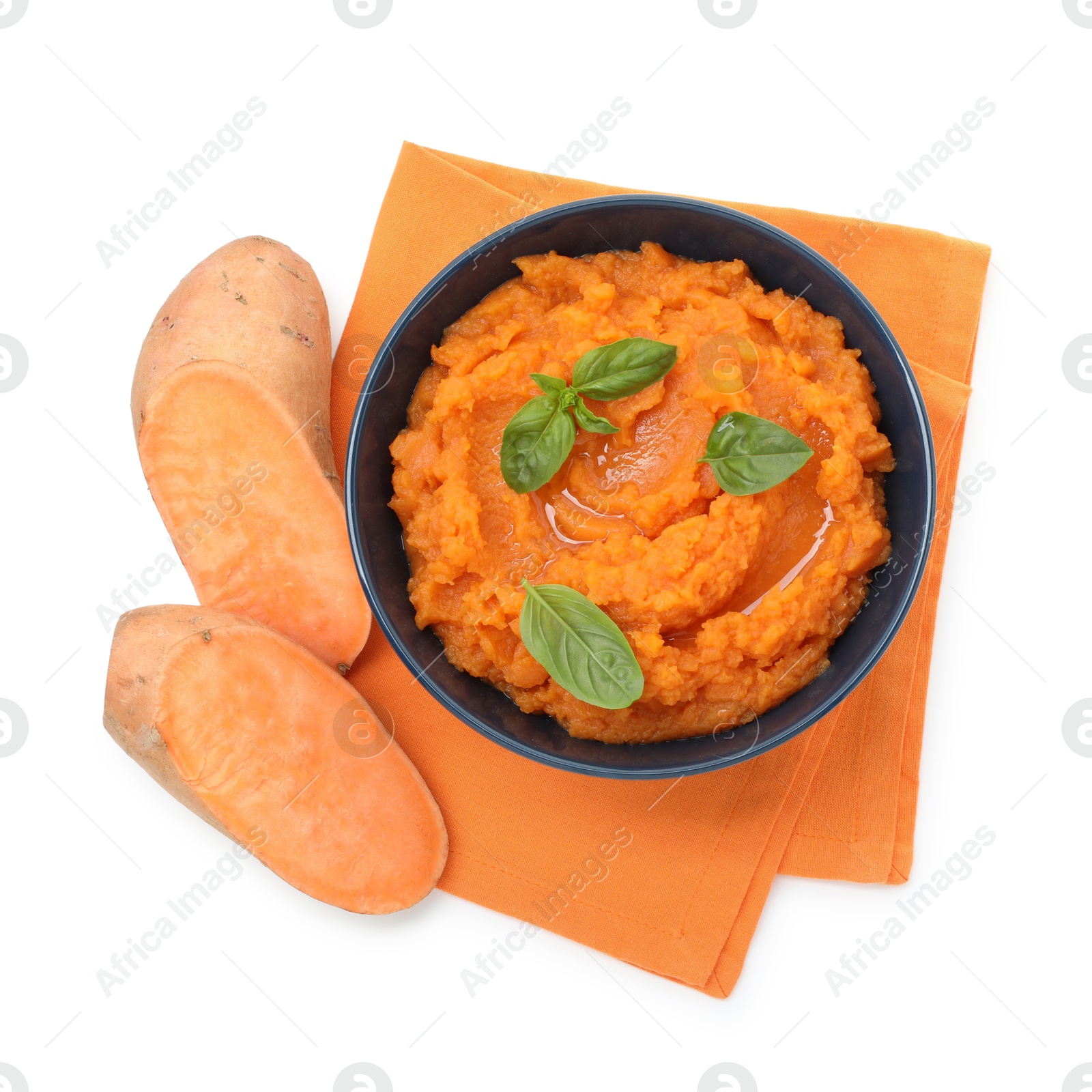 Photo of Tasty mashed sweet potato with basil in bowl and cut vegetables isolated on white, top view