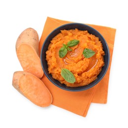 Photo of Tasty mashed sweet potato with basil in bowl and cut vegetables isolated on white, top view