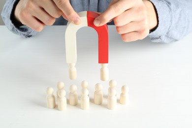 Photo of Man with magnet attracting game pieces at white table, closeup