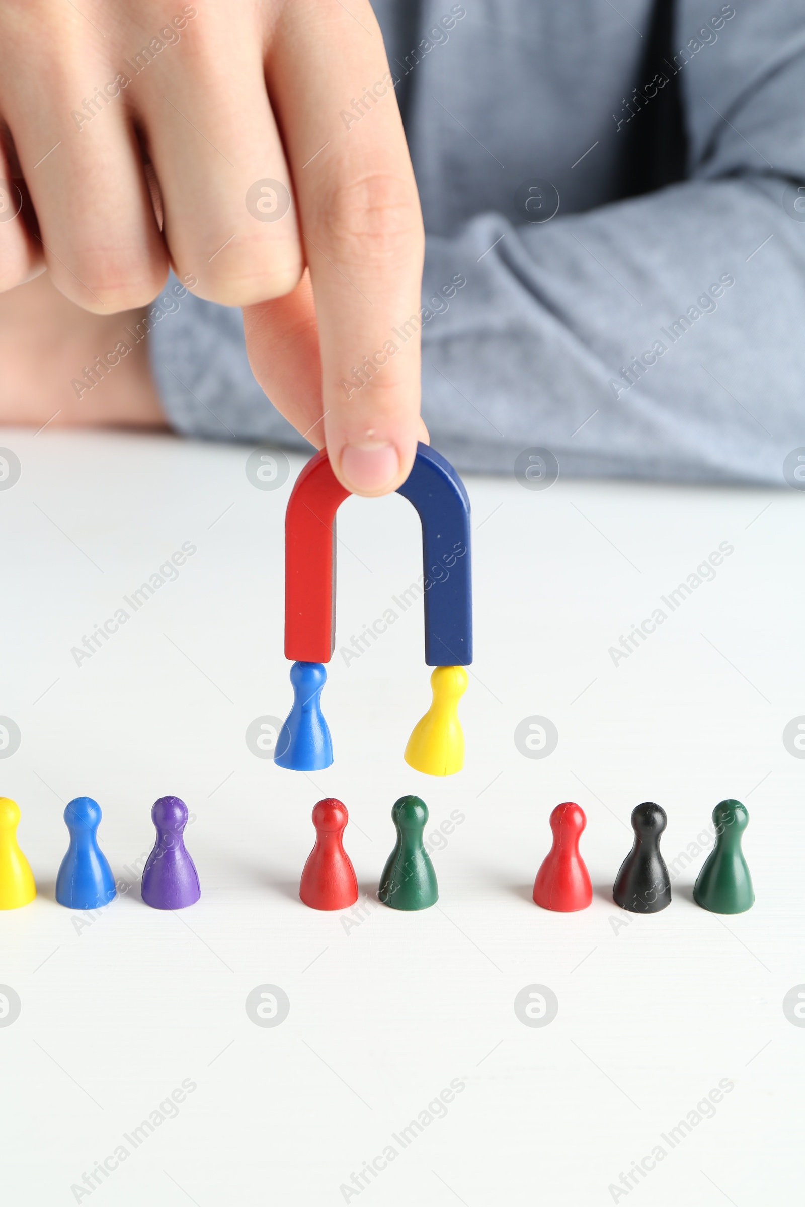 Photo of Man with magnet attracting game pieces at white table, closeup