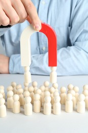 Photo of Man with magnet attracting game pieces at white table, closeup