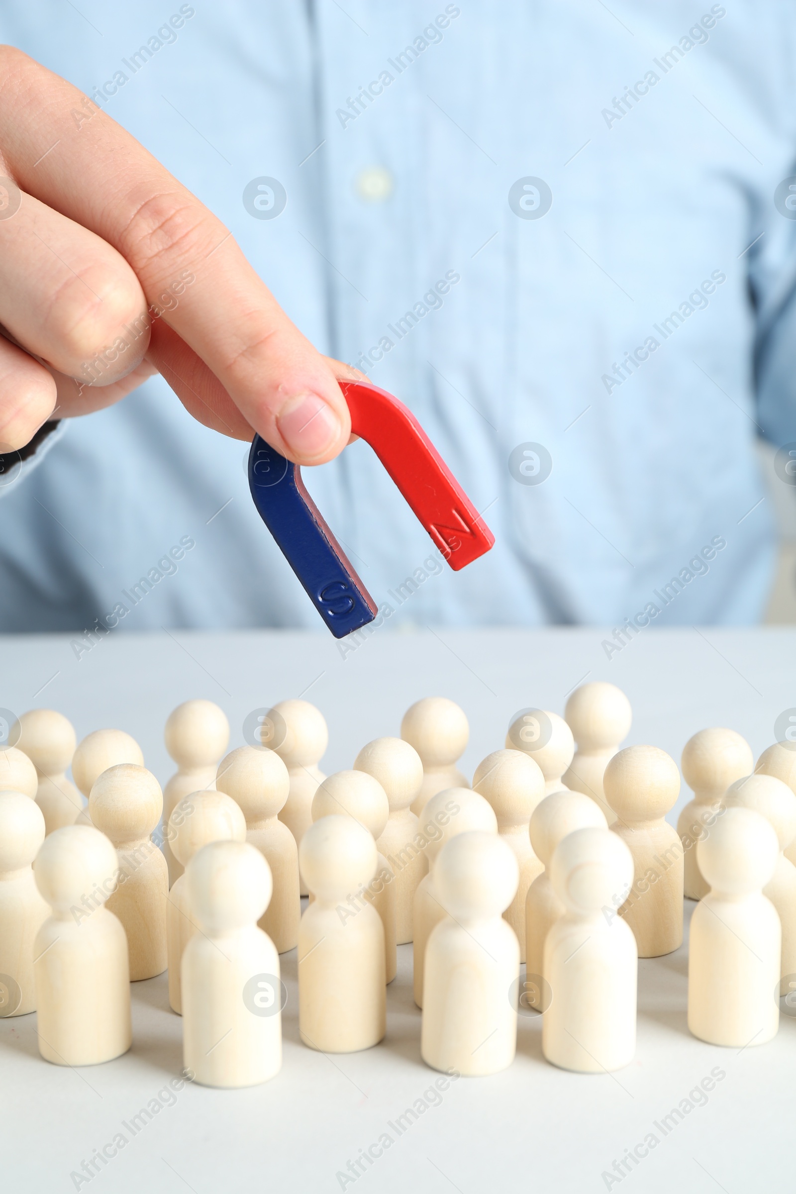 Photo of Man with magnet attracting game pieces at white table, closeup