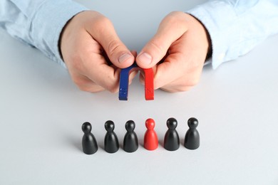 Photo of Man with magnet attracting game pieces at white table, closeup