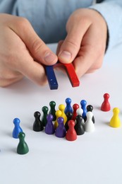 Photo of Man with magnet attracting game pieces at white table, closeup