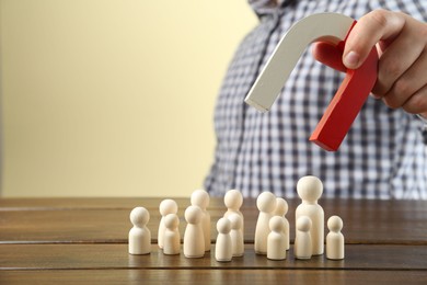 Photo of Man with magnet attracting game pieces at wooden table, closeup. Space for text