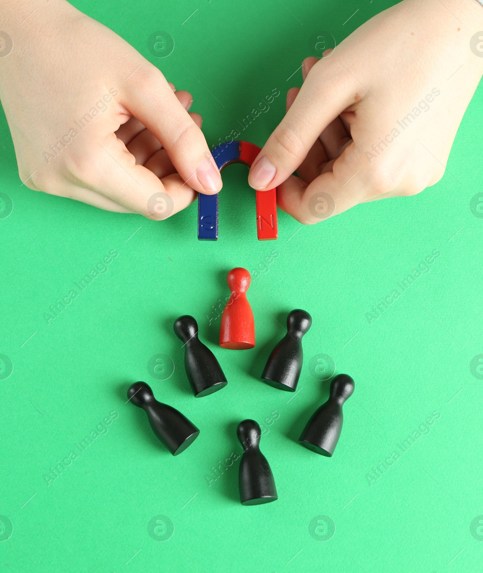 Photo of Woman with magnet attracting game pieces at green table, above view