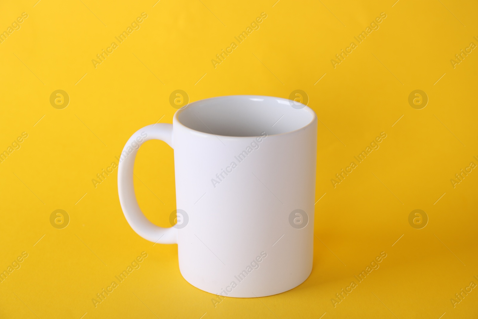 Photo of One blank white mug on yellow background. Mockup for design