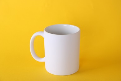 Photo of One blank white mug on yellow background. Mockup for design