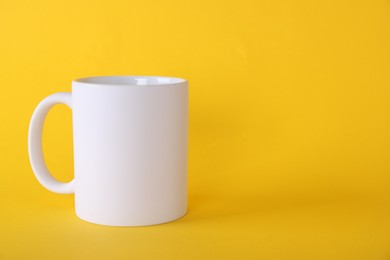 Photo of One blank white mug on yellow background. Mockup for design