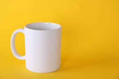 Photo of One blank white mug on yellow background. Mockup for design