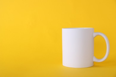 Photo of One blank white mug on yellow background. Mockup for design