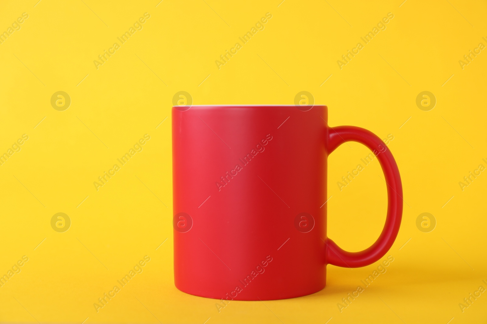 Photo of One blank red mug on yellow background. Mockup for design