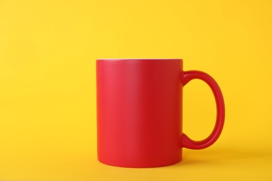 Photo of One blank red mug on yellow background. Mockup for design