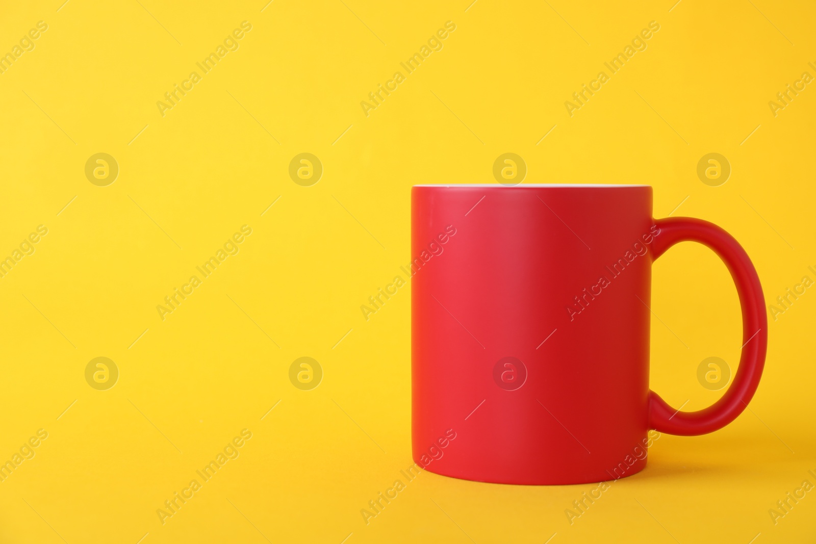 Photo of One blank red mug on yellow background. Mockup for design