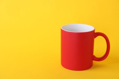 Photo of One blank red mug on yellow background. Mockup for design