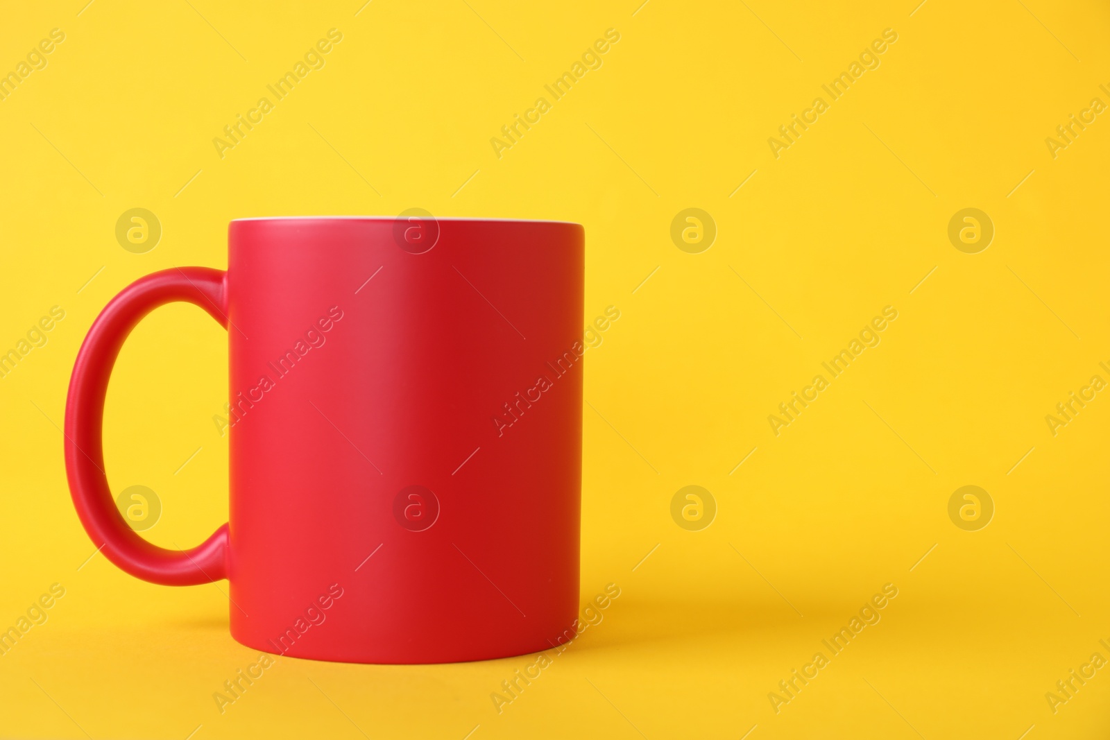 Photo of One blank red mug on yellow background. Mockup for design