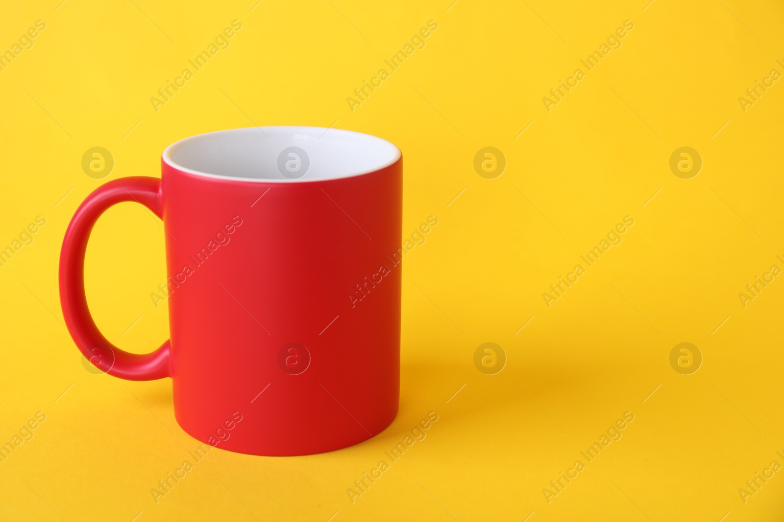 Photo of One blank red mug on yellow background. Mockup for design