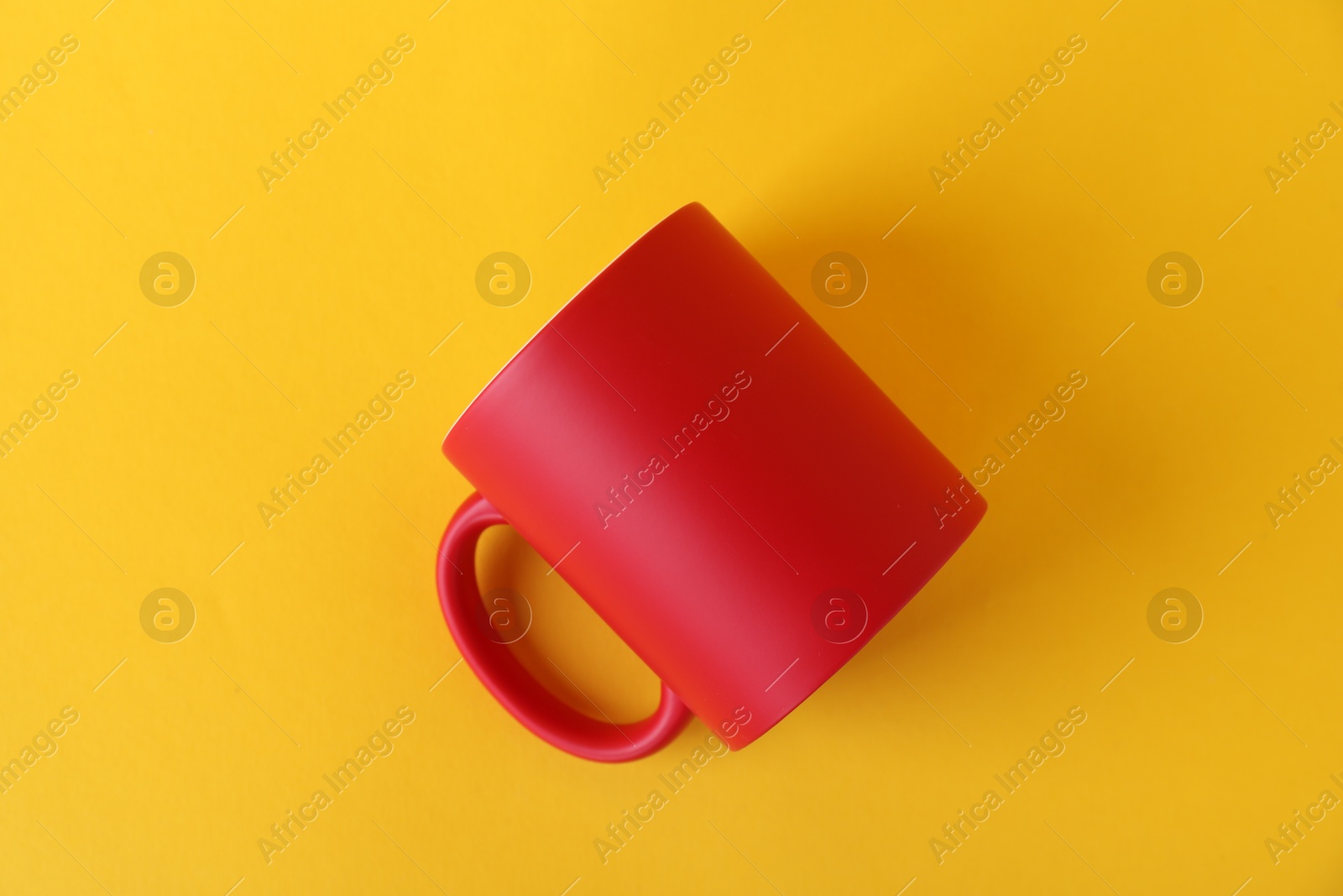 Photo of One blank red mug on yellow background, top view. Mockup for design