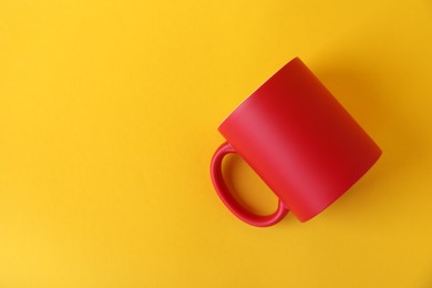 Photo of One blank red mug on yellow background, top view. Mockup for design