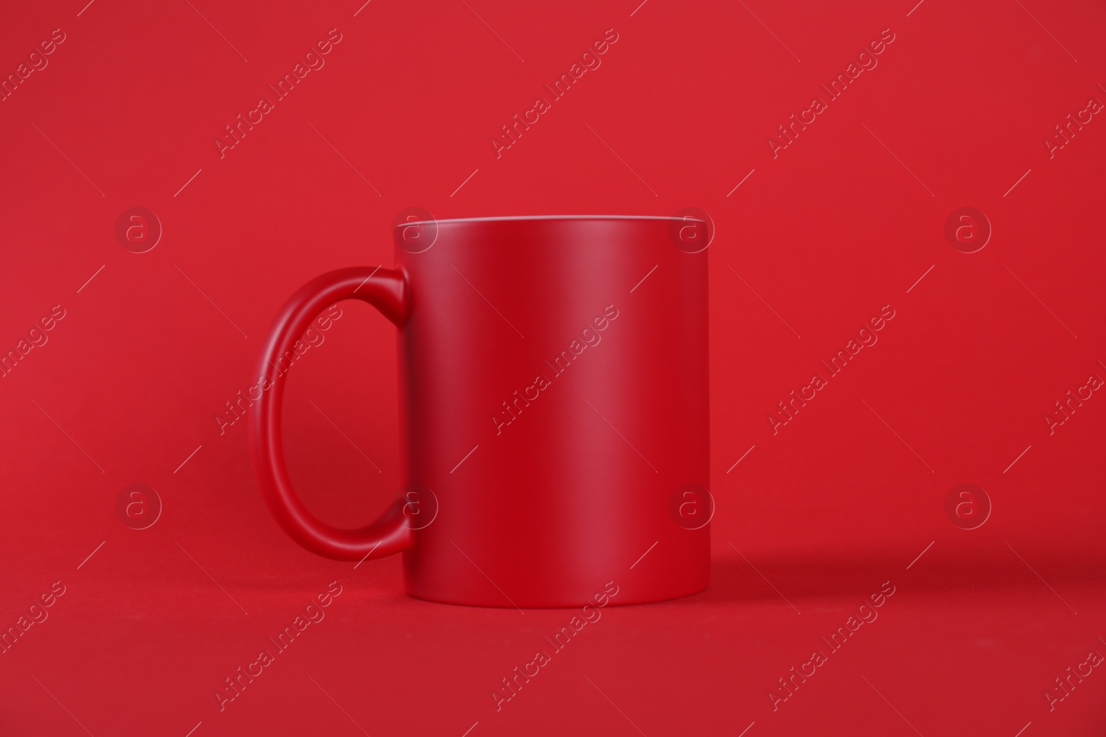 Photo of One blank mug on red background. Mockup for design