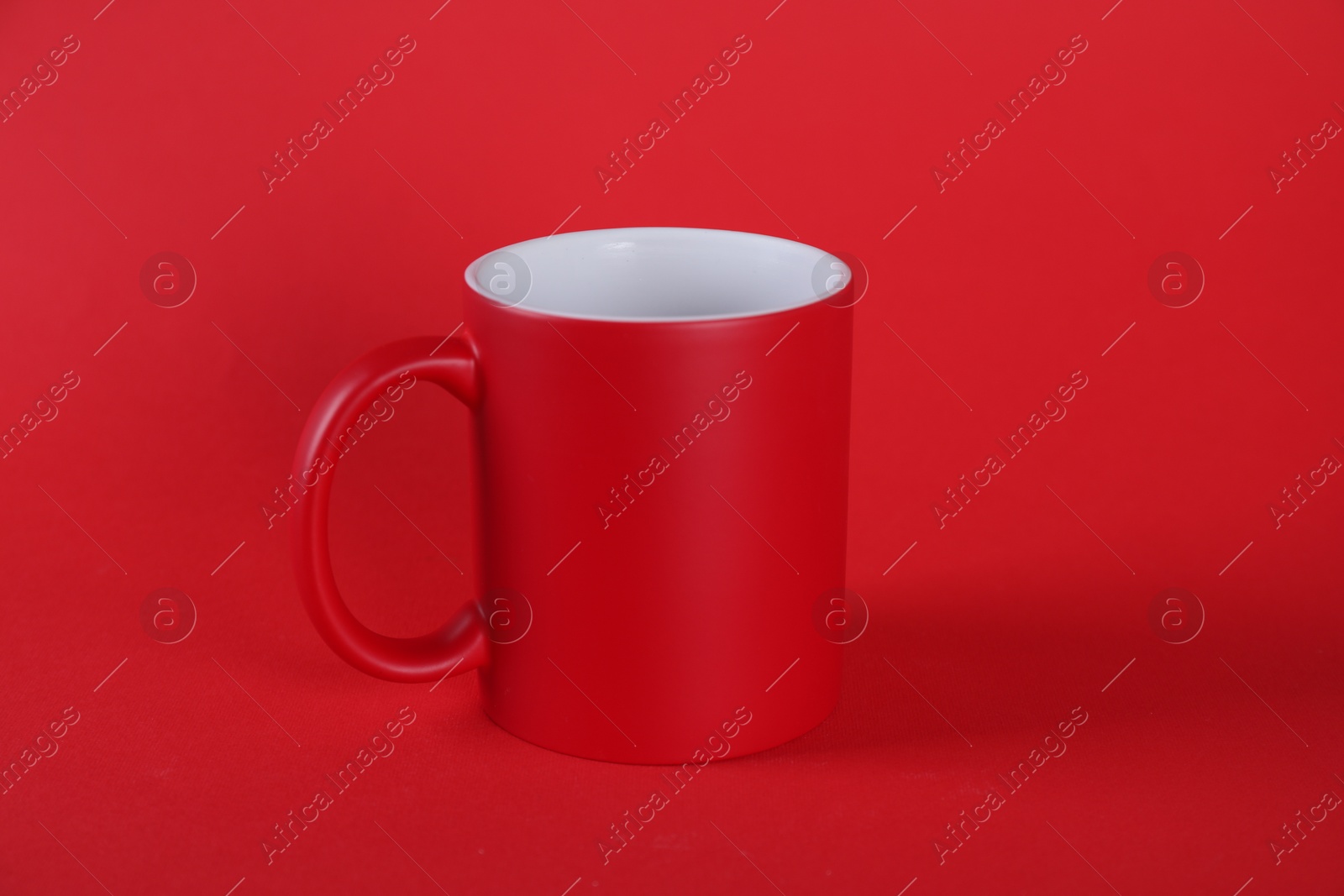 Photo of One blank mug on red background. Mockup for design