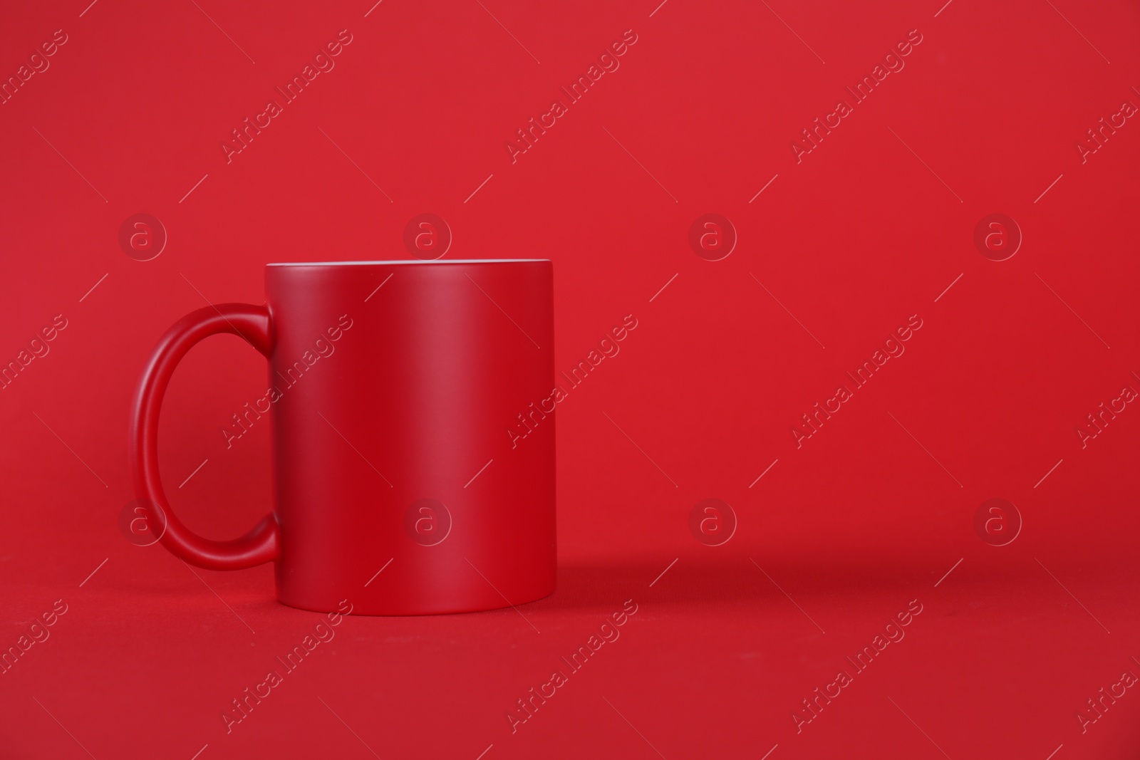 Photo of One blank mug on red background. Mockup for design