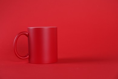 Photo of One blank mug on red background. Mockup for design